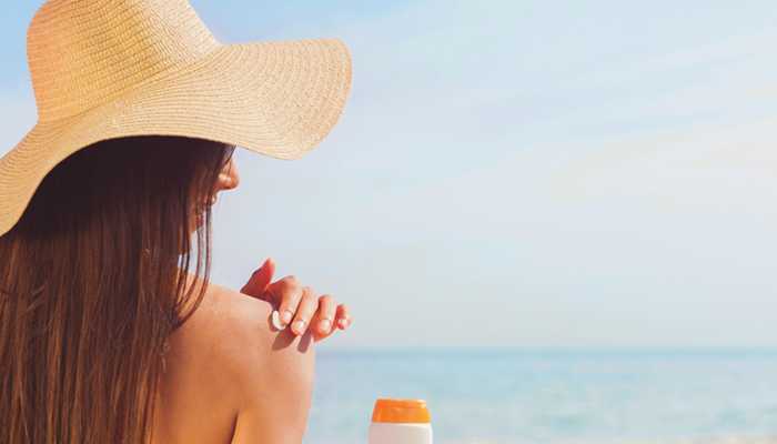 Image of woman applying sunscreen to her shoulder