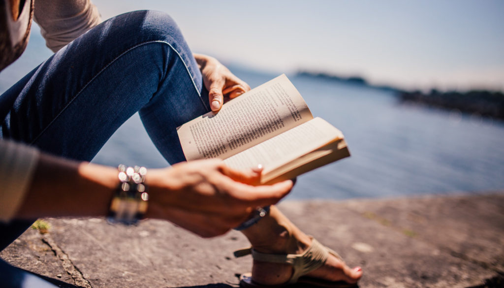 Image of woman reading book on pier