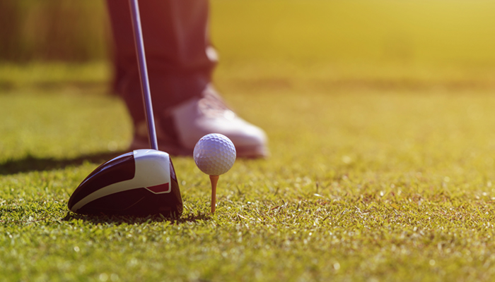 Image of a man playing golf in green course. Focus on golf ball