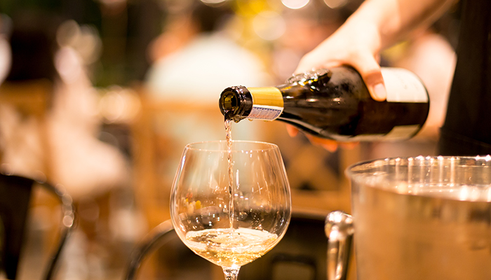 Shot in high iso with low light man pouring wine from the bottle into a glass at the party