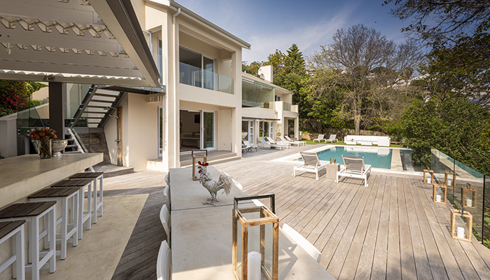 Spacious outdoor entertainment deck at Number Eleven villa with bar seating, pool, and surrounding forest