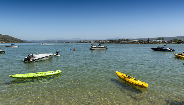 Kayaks and boats floating in the calm waters of the Knysna lagoon near The Milkwood Collection