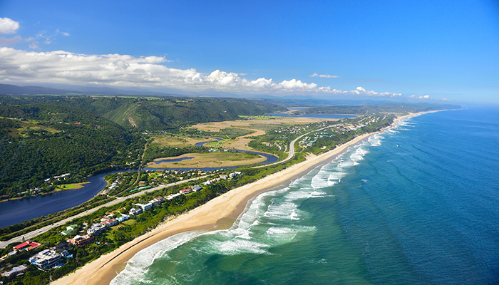 Aerial view of Wilderness beach, lush hills, and coastline along South Africa’s Garden Route