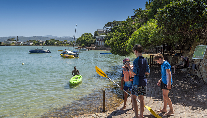 Kids with paddles beside Knysna Lagoon, ready for kayaking near The Milkwood Collection