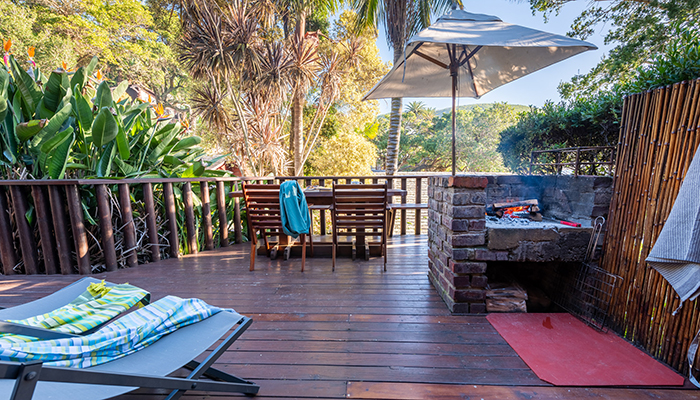 Deck at The Milkwood Collection with braai area, dining table, and garden view