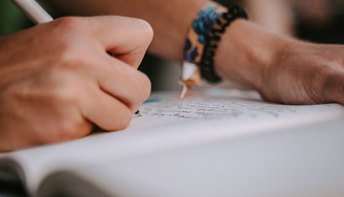Close-up of hand writing in a notebook with a pen