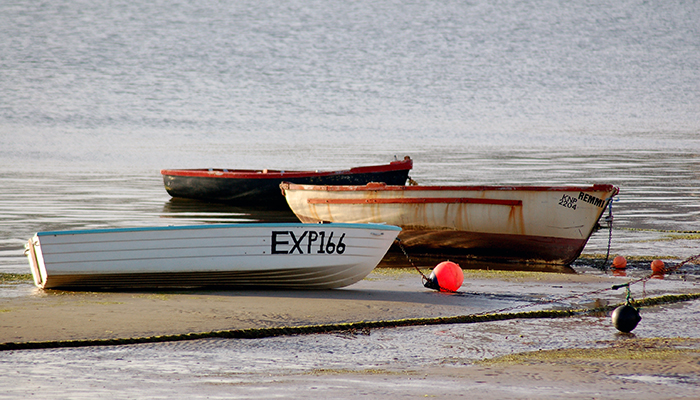Three small boats resting on the sand during low tide at Thesen Island in Knysna.