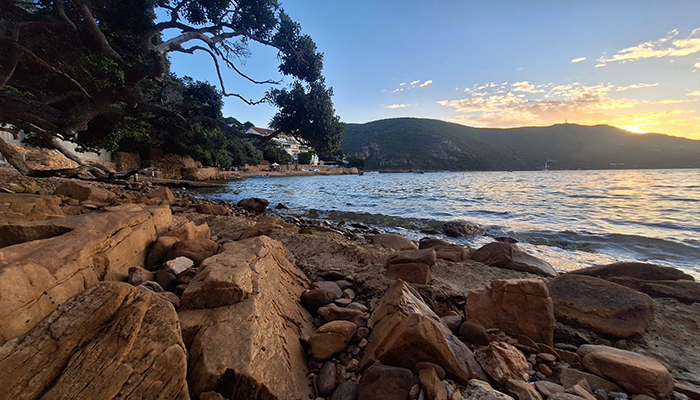 Rocky shoreline at dusk with golden light over the lagoon in Knysna