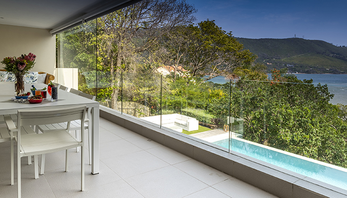 Number Eleven villa patio with outdoor dining area, glass balustrades, and lagoon views overlooking a private pool.