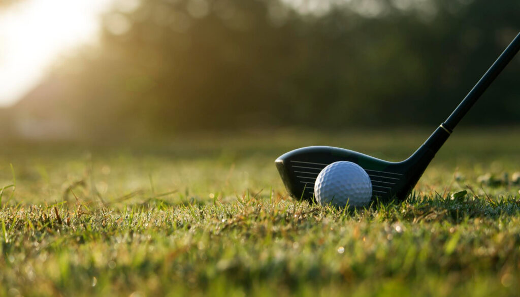Golf club and ball on a course in warm morning light